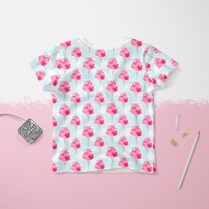 May include: A white t-shirt with a light blue background and a repeating pattern of pink flower bouquets.