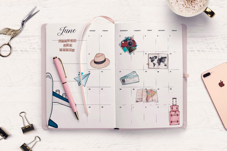 May include: A pink open planner with a monthly calendar layout for June. The planner has a pink pen, a paper airplane, a hat, a camera, a world map, a plane ticket, a map, and a suitcase drawn on it. The planner has the words "Travel the World" written on it.