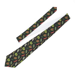 Op de afbeelding: Een zwarte stropdas met een herhalend patroon van groene, rode en gele bladeren en plantvormen. De stropdas is gemaakt van een gladde stof en heeft een witte voering. Een stijlvol accessoire voor elke gelegenheid.