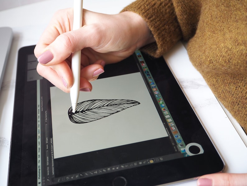 May include: A person using a white stylus to draw a black and white feather on a digital tablet.