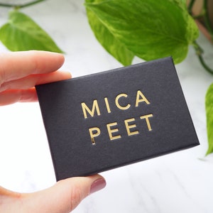 May include: A black box with the words "MICA PEET" printed in gold lettering.