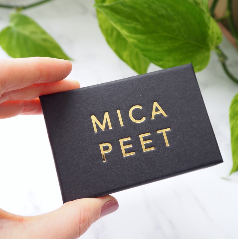 May include: A black box with the words "MICA PEET" printed in gold lettering.