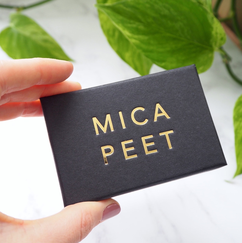 May include: A black box with the words "MICA PEET" printed in gold lettering.