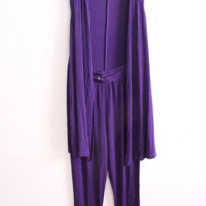 Puede incluir: Un conjunto de dos piezas morado con una chaqueta sin mangas y pantalones a juego. La chaqueta tiene un dise&ntilde;o drapeado y los pantalones tienen una pierna recta.