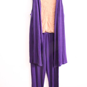 Puede incluir: Un conjunto de tres piezas en morado y melocot&oacute;n. El conjunto incluye una chaqueta larga sin mangas, un top sin mangas y pantalones. La chaqueta y los pantalones son de un morado intenso, mientras que el top es de color melocot&oacute;n.