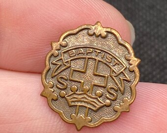 May include: A gold-toned metal pin with a cross and crown design. The pin says "Baptist" around the edge.