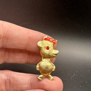 May include: Gold-toned teddy bear brooch with red bow and red rhinestone eyes.