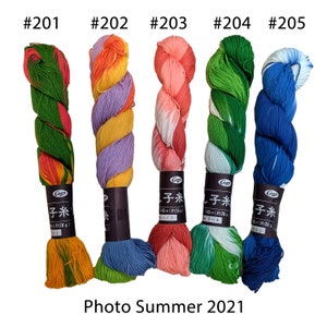 Può includere: Cinque matasse di filo da ricamo in diverse combinazioni di colori. Il filo è avvolto su bobine di cartone con il marchio "Ciren" e il testo "子糸" (giapponese per "filo da ricamo") stampato sulle bobine. Ogni bobina è etichettata con un numero da 201 a 205.