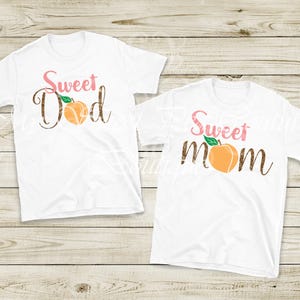 two white t-shirts with the text "Sweet Dad Sweet Mom" printed on them, along with an orange peach graphic.