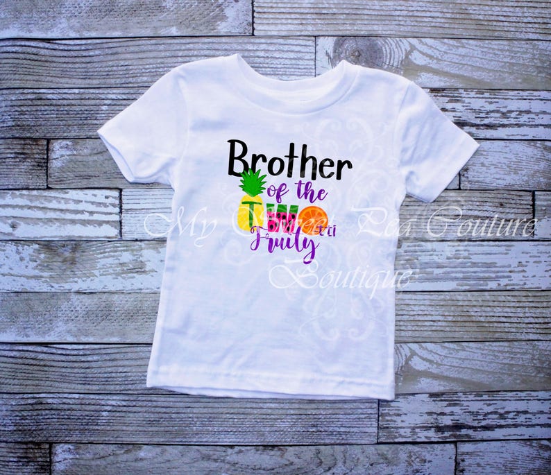 A white t-shirt with a graphic design featuring a pineapple and the text "Brother of the Two Fruits" printed on it.