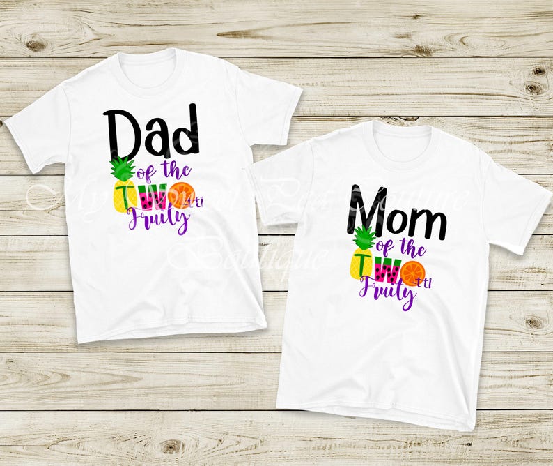 Two white t-shirts with colorful text and graphics printed on them, one for a father and one for a mother.