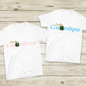Two white t-shirts with the text "Lucky Grandma" printed on them, along with a four-leaf clover symbol.