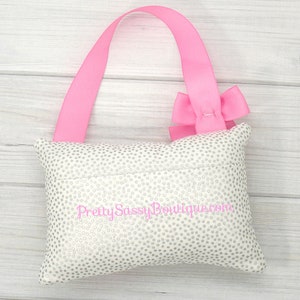 May include: A white pillow with silver glitter dots and a pink ribbon bow. The pillow has a pink ribbon loop for hanging and the text "Pretty Sassy Boutique.com" is embroidered on the front.