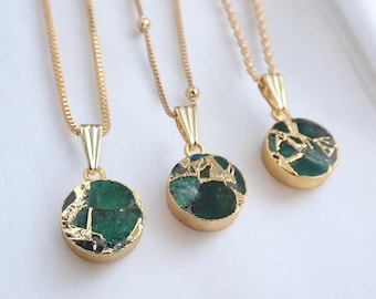 May include: Three gold-toned necklaces, each featuring a circular pendant with a dark green, textured stone inlay framed in gold metal. The pendants hang from delicate gold-toned chains, showcasing a consistent design across all three pieces.