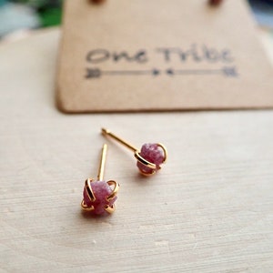 Puede incluir: Un par de pendientes de bot&oacute;n de oro con piedras preciosas rosadas sin cortar. Las piedras preciosas est&aacute;n engastadas en una jaula de oro.