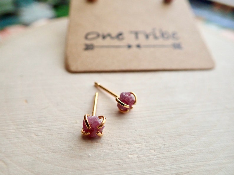 Puede incluir: Un par de pendientes de bot&oacute;n de oro con piedras preciosas rosadas sin cortar. Las piedras preciosas est&aacute;n engastadas en una jaula de oro.