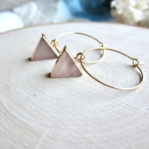 May include: A pair of gold hoop earrings with a pink triangle pendant on each hoop.