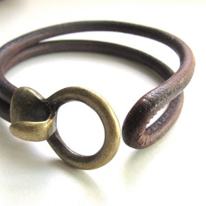 May include: A brown leather bracelet with a brass clasp. The bracelet is double-layered and has a rustic look.