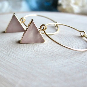 May include: Gold hoop earrings with a pink triangle pendant. The triangle is made of a pearlescent material.