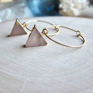 May include: Gold hoop earrings with a pink triangle pendant. The triangle is made of a pearlescent material.
