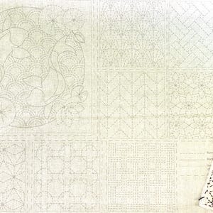 Könnte beinhalten: Ein weißer Stoff mit verschiedenen gestickten Mustern, darunter Fische, Blumen und geometrische Muster. Der Stoff ist in neun Quadrate unterteilt, jedes mit einem anderen Muster. Ein kleineres Stoffquadrat mit einem schwarz-weißen geometrischen Muster befindet sich in der rechten unteren Ecke.