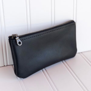 May include: A black leather zippered pouch with a silver zipper pull.