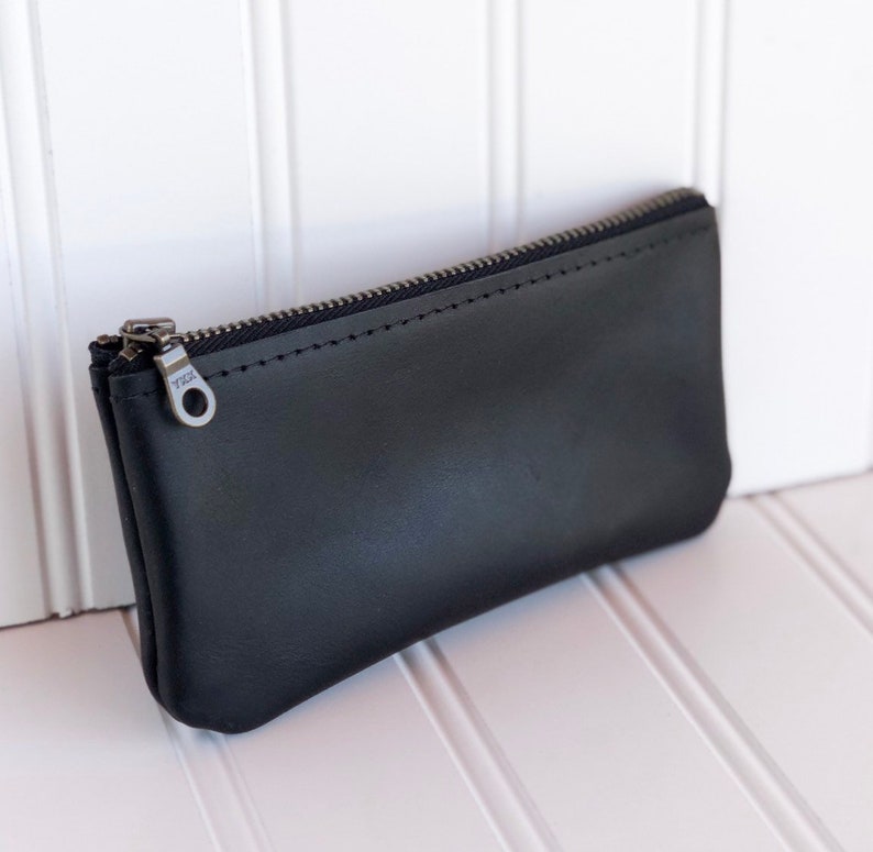 May include: A black leather zippered pouch with a silver zipper pull.