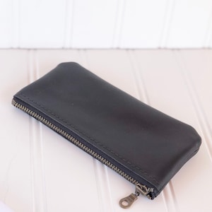 May include: A black leather zippered pouch with a silver zipper pull.