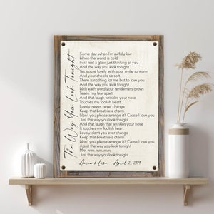May include: A rustic wood sign with a white background and black text. The text is a song lyric about love and features the lyrics "The Way You Look Tonight". The sign is dated "April 2, 2019" and signed "Aaron & Lisa".