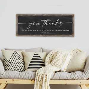 May include: A rustic wooden sign with a black chalkboard background. The sign reads "give thanks to the Lord for he is good. His love endures forever. Psalm 107:1".