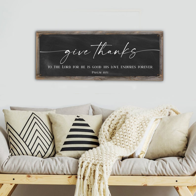 May include: A rustic wooden sign with a black chalkboard background. The sign reads "give thanks to the Lord for he is good. His love endures forever. Psalm 107:1".