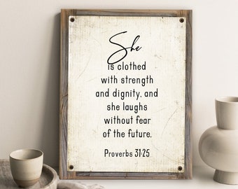 May include: A rustic wood framed sign with a white background and black text. The text reads "She is clothed with strength and dignity, and she laughs without fear of the future. Proverbs 31:25".