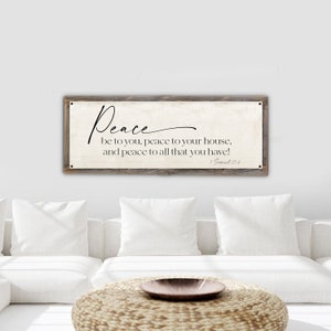 May include: A rustic wooden sign with a white background and black text. The sign reads "Peace be to you, peace to your house, and peace to all that you have!" with the scripture reference "1 Samuel 25:6".