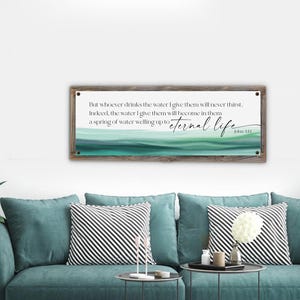 May include: A rectangular wooden framed wall art piece with a white background and text from John 4:14. The artwork features a watercolor design in shades of green and blue, with the words "eternal life" in cursive.