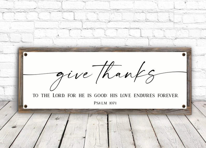 May include: A white wooden sign with black text that reads "give thanks to the Lord for he is good. His love endures forever. Psalm 107:1".