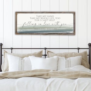 May include: A rustic wooden sign with a watercolor background in shades of blue and green. The sign features the text "TAKE MY HAND TAKE MY WHOLE LIFE, TOO FOR I CAN'T HELP falling in love with you" with the names "MARK & JENNA" and the date "JUNE 21, 2019" below.