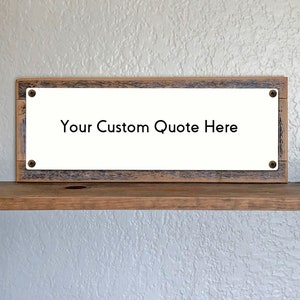 May include: A rectangular wooden sign with the text "Your Custom Quote Here" in black. The sign has a white background and is framed by a rustic, weathered wood. Four screws secure the white panel to the frame.