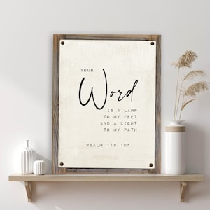 May include: A white canvas print with a wooden frame. The print features black text that reads "YOUR Word IS A LAMP TO MY FEET AND A LIGHT TO MY PATH PSALM 119:105".
