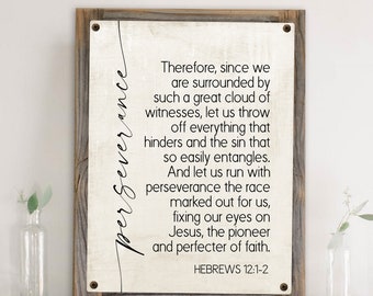 May include: A wood framed print with a white background and black text. The text reads "Therefore, since we are surrounded by such a great cloud of witnesses, let us throw off everything that hinders and the sin that so easily entangles. And let us run with perseverance the race marked out for us, fixing our eyes on Jesus, the pioneer and perfecter of faith. Hebrews 12:1-2"