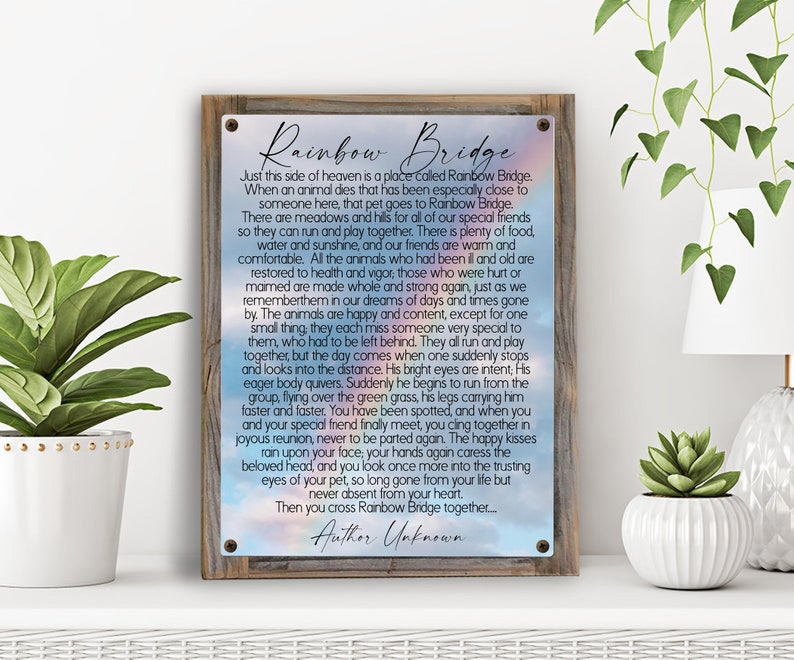 May include: A wooden sign with a rainbow background and the text "Rainbow Bridge". The sign features a poem about the passing of pets and their journey to a place called Rainbow Bridge where they can play and be happy again. The poem ends with the words "Then you cross Rainbow Bridge together... Author Unknown."