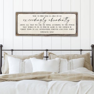 May include: A rustic wooden sign with a white background and black text. The sign reads "NOW TO HIM WHO IS ABLE TO DO exceedingly abundantly ABOVE ALL THAT WE ASK OR THINK. ACCORDING TO THE POWER THAT WORKS IN US TO HIM BE GLORY IN THE CHURCH BY CHRIST JESUS TO ALL GENERATIONS FOREVER AND EVER. AMEN EPHESIANS 320-21".