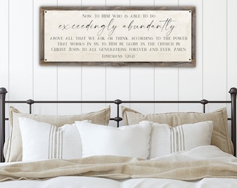 May include: A rustic wooden sign with a white background and black text. The sign reads "NOW TO HIM WHO IS ABLE TO DO exceedingly abundantly ABOVE ALL THAT WE ASK OR THINK. ACCORDING TO THE POWER THAT WORKS IN US TO HIM BE GLORY IN THE CHURCH BY CHRIST JESUS TO ALL GENERATIONS FOREVER AND EVER. AMEN EPHESIANS 320-21".