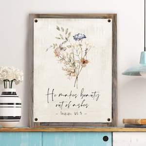 May include: A watercolor floral bouquet with a beige background and a wooden frame. The text reads "He makes beauty out of ashes - Isaiah 61:3 - "