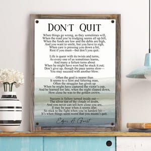 May include: A motivational poem titled "Don't Quit" printed on a wood sign with a blue and white watercolor background. The poem encourages perseverance and resilience in the face of challenges.