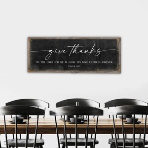 May include: A black and white sign with a rustic wood frame. The sign says "give thanks to the Lord for he is good; his love endures forever. Psalm 1071".