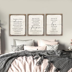 May include: Three wooden signs with white backgrounds and black text. The signs feature bible verses from Colossians 3:12-14. The first sign says "Therefore, as God's chosen people, holy and dearly loved, clothe yourselves with compassion, kindness, humility, gentleness and patience. Colossians 3:12". The second sign says "Bear with each other and forgive one another if any of you has a grievance against someone. Forgive as the Lord forgave you. Colossians 3:13". The third sign says "And over all these virtues put on love which binds them all together in perfect unity. Colossians 3:14".