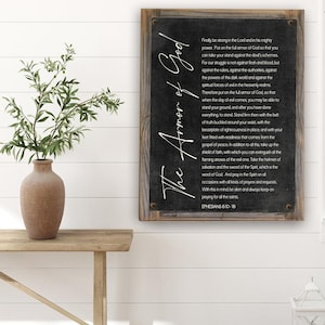 K&ouml;nnte beinhalten: Ein schwarz-wei&szlig;es Schild mit einem Holzrahmen. Das Schild zeigt ein Zitat aus Epheser 6,10-18 &uuml;ber die R&uuml;stung Gottes. Der Text ist in einer stilisierten Schriftart geschrieben und enth&auml;lt die Worte "Die R&uuml;stung Gottes".