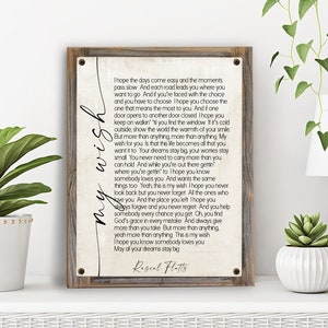 May include: A rustic wooden sign with a white background and black text. The sign features a song lyric by Rascal Flatts, "My Wish." The lyrics are about hope, dreams, and finding your way in life.