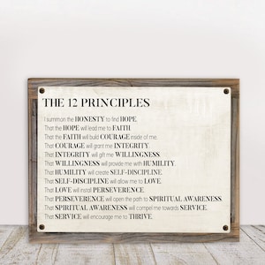 May include: A rustic wooden sign with white text that reads "THE 12 PRINCIPLES" and lists 12 principles of personal growth, including honesty, hope, faith, courage, integrity, willingness, humility, self-discipline, love, perseverance, spiritual awareness, service, and thrive.