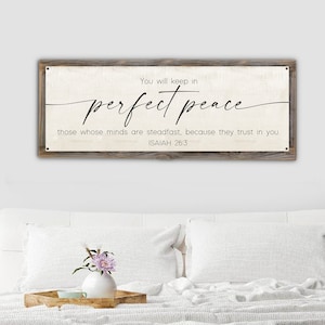 May include: A rustic wooden sign with a white background and black text. The sign reads "You will keep in perfect peace those whose minds are steadfast, because they trust in you. ISAIAH 26:3".